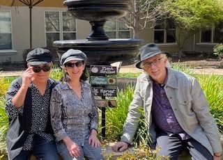 Three people wearing hats by fountain