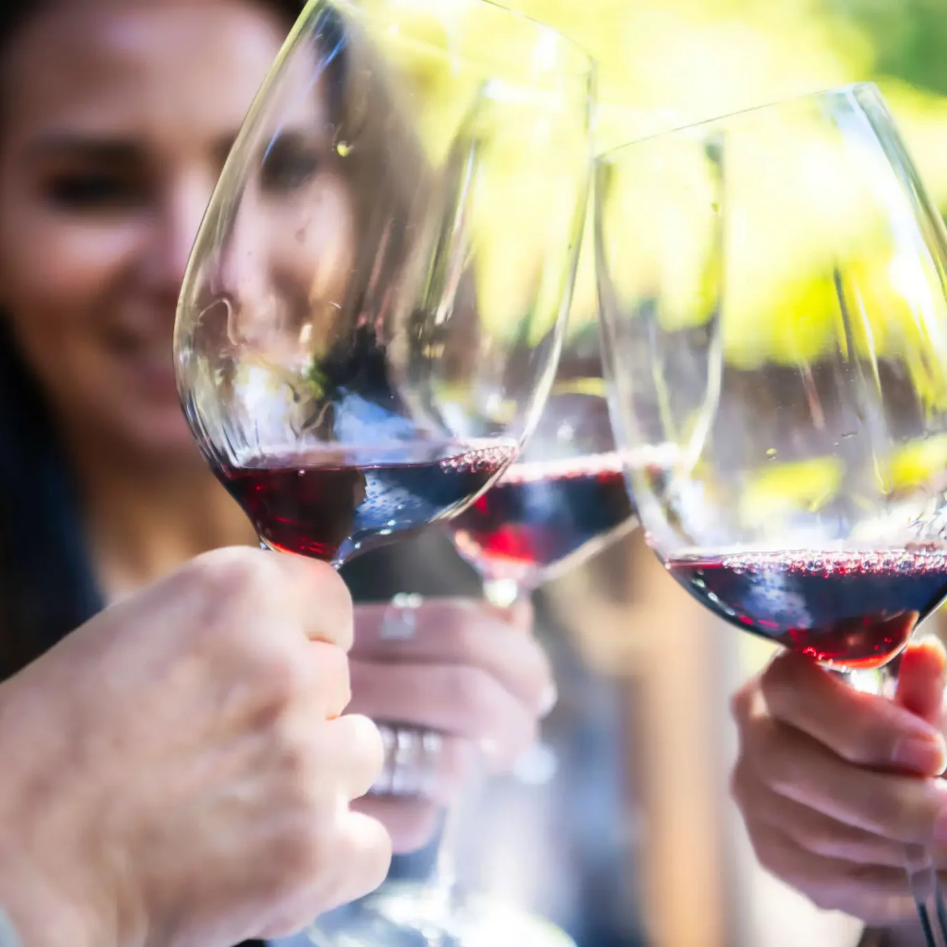 People clinking glasses of red wine
