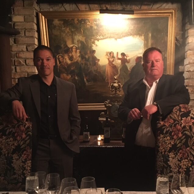 Two men in suits beside large framed painting